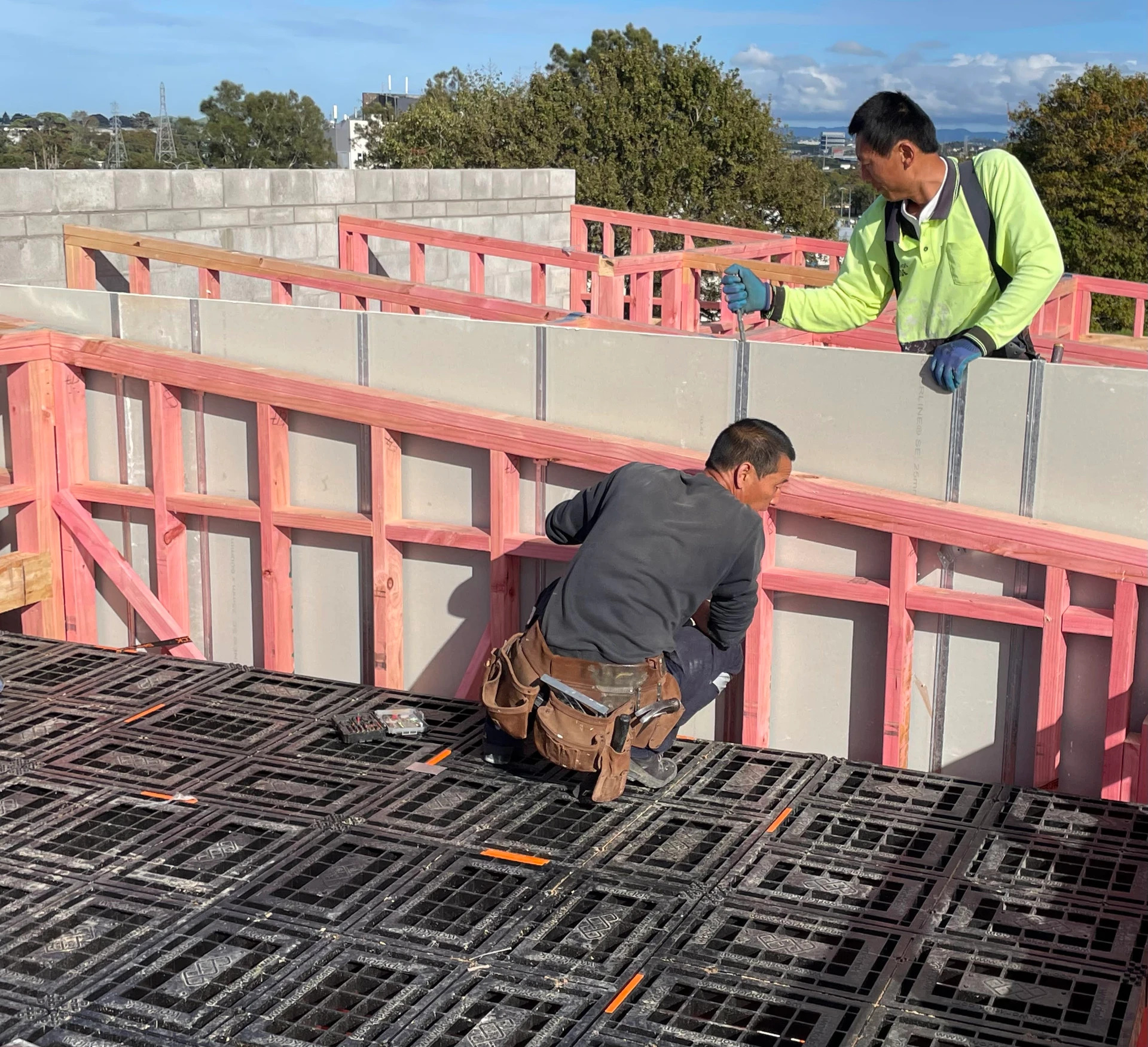 Builders positioning prefabricated wall panels from a platform at a multi-unit site