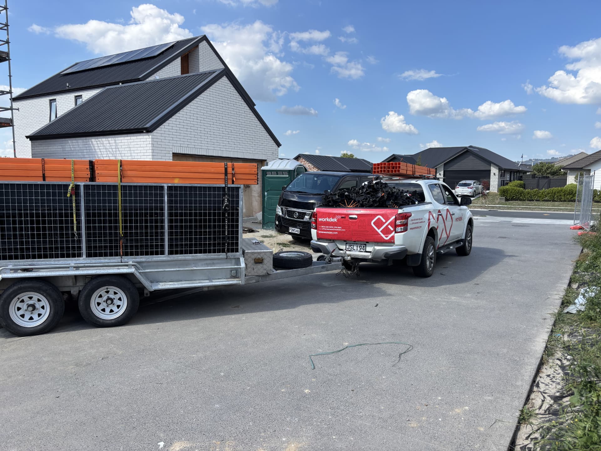 Workdek ute towing a trailer loaded with orange legs and deck panels