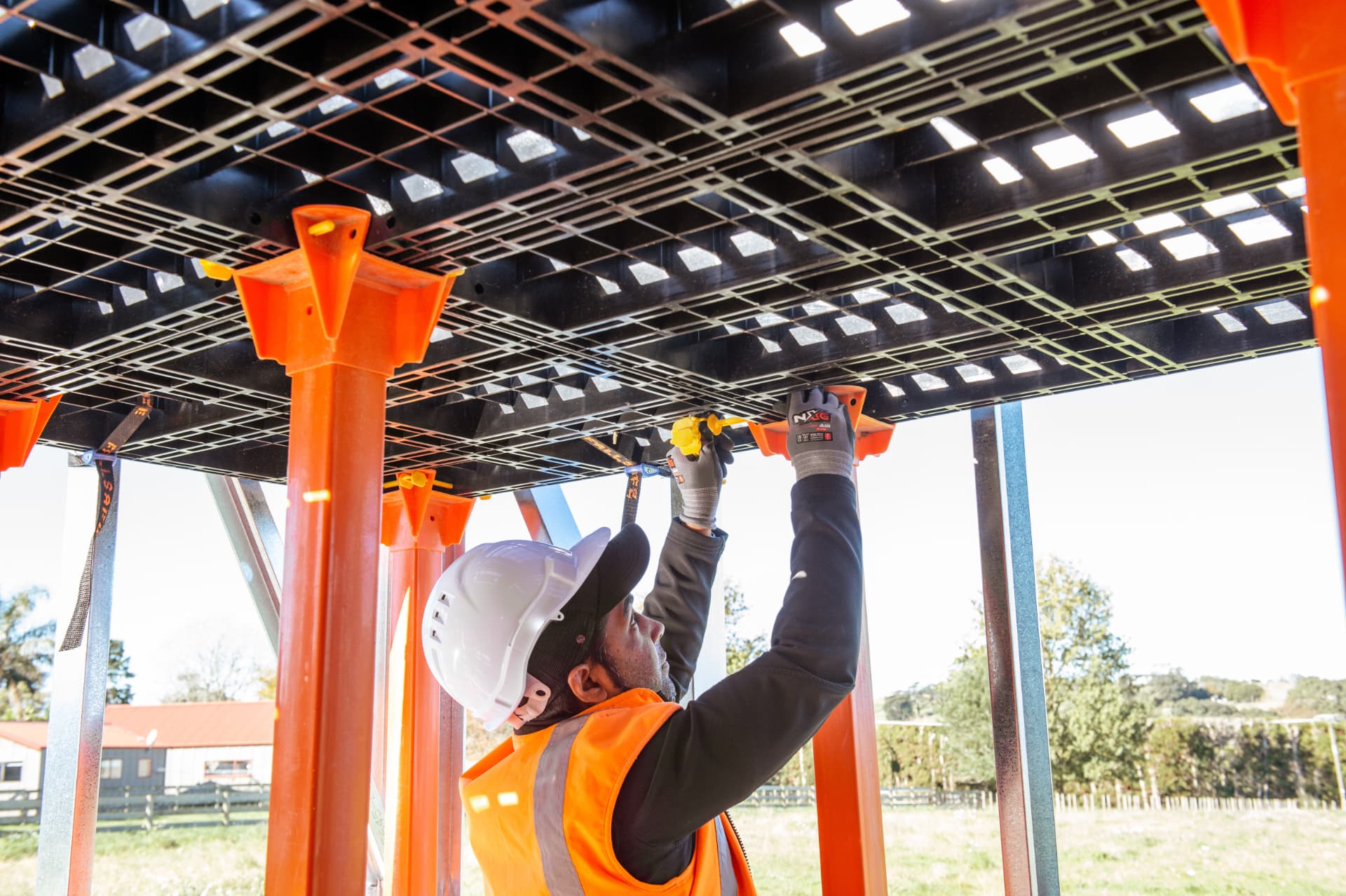 Installer securing a Workdek panel into an orange cradle from below