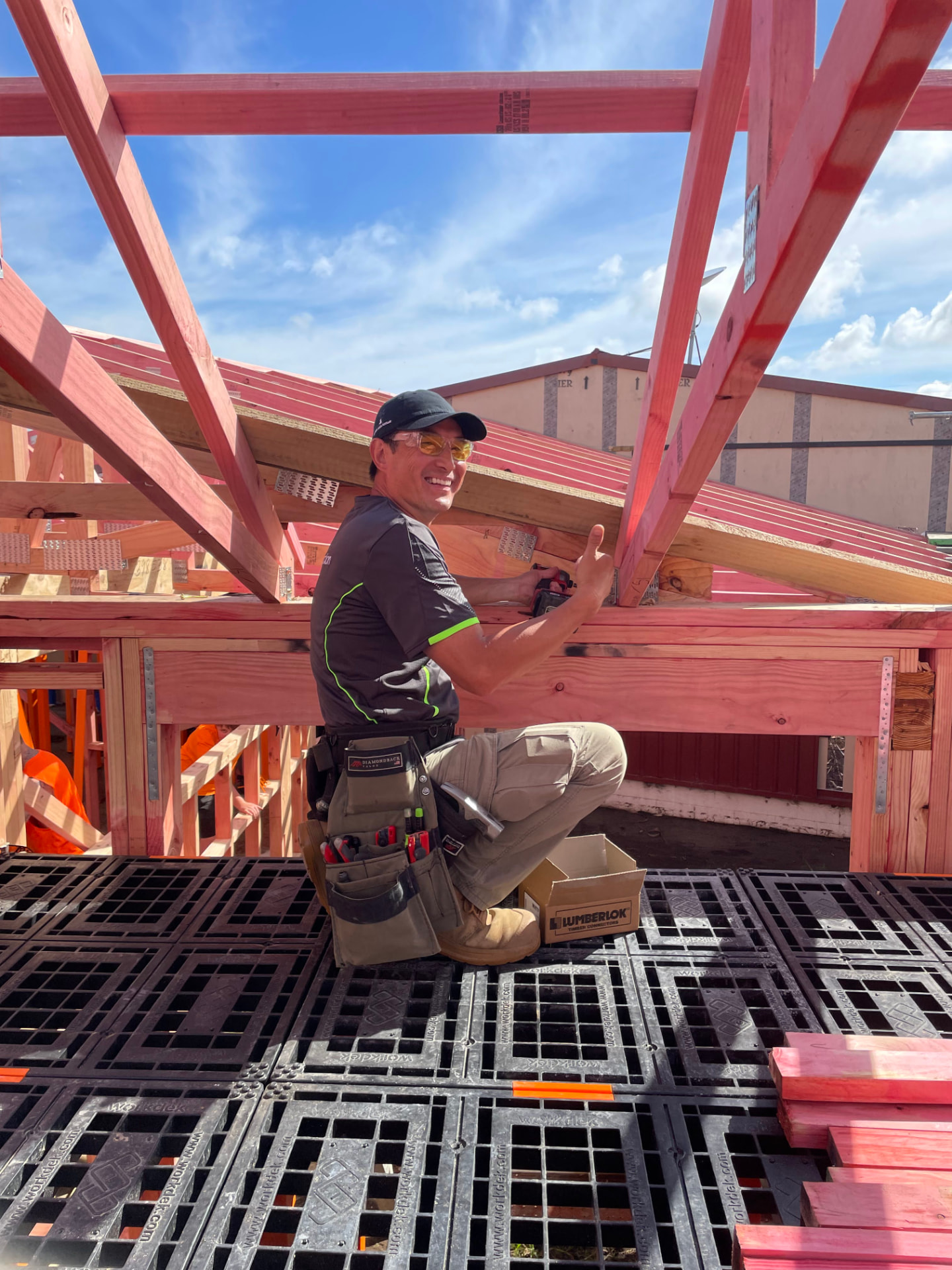 Builder kneeling on a Workdek deck while fixing timber roof framing