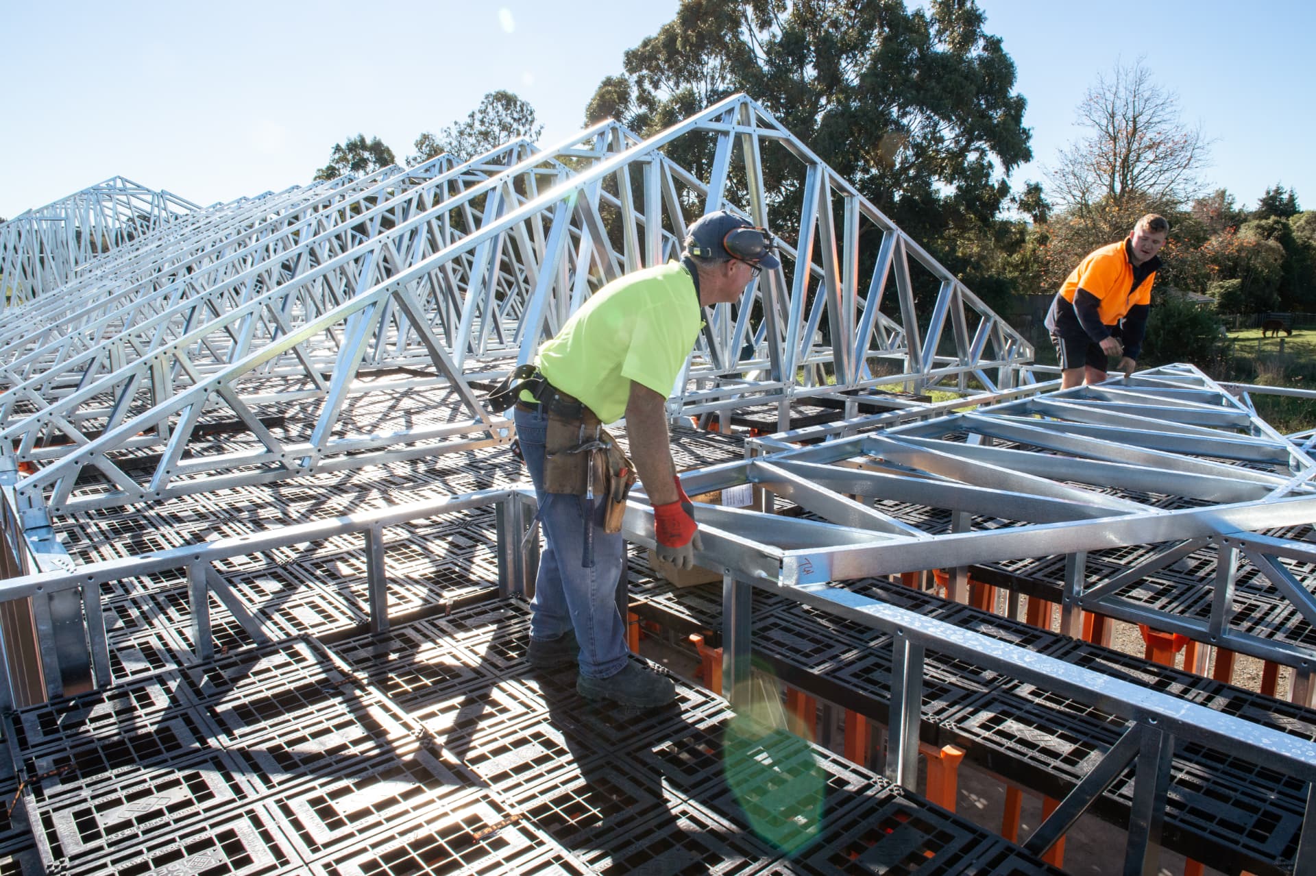 Crews installing steel roof trusses over Workdek decks on a Tuakau site